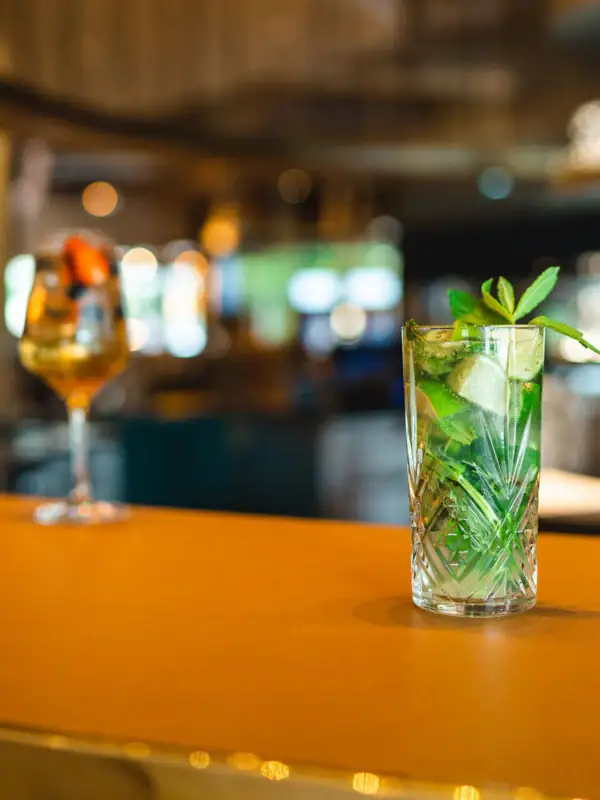 Een glas met vloeistof en een groen blad erop.