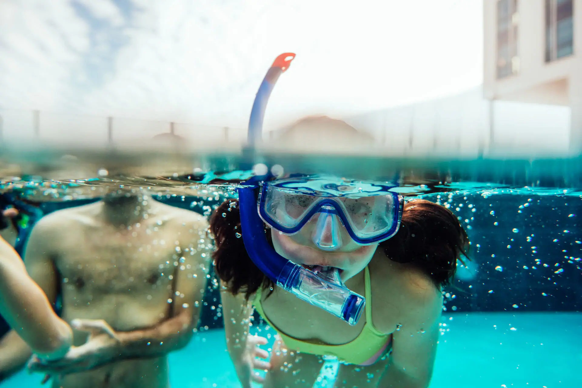 Een vrouw in zwemkleding en met zwembril onder water.