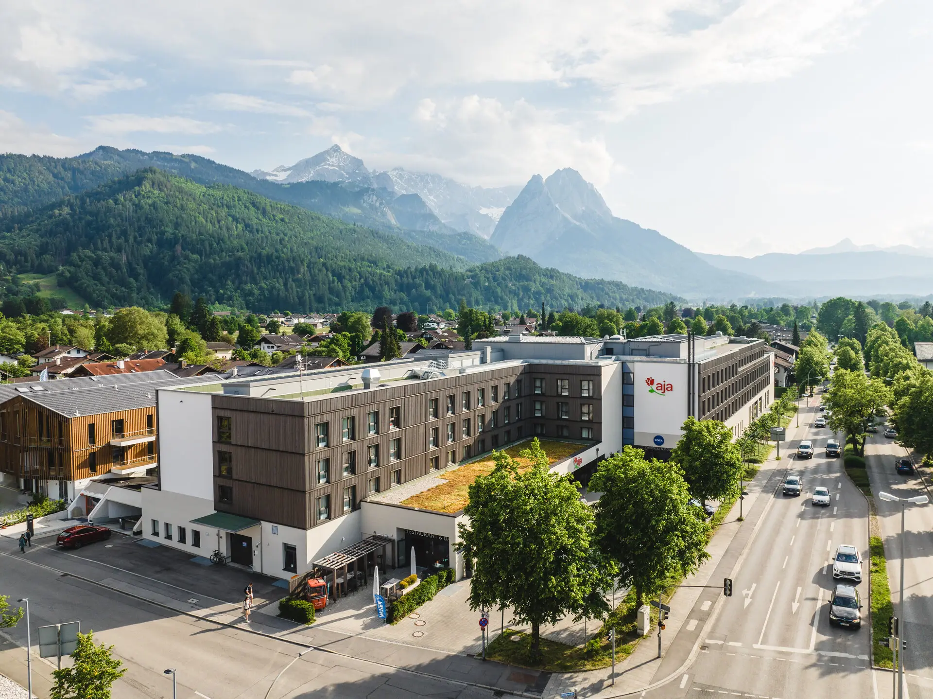 aja Garmisch-Partenkirchen Een gebouw met bomen en bergen op de achtergrond.