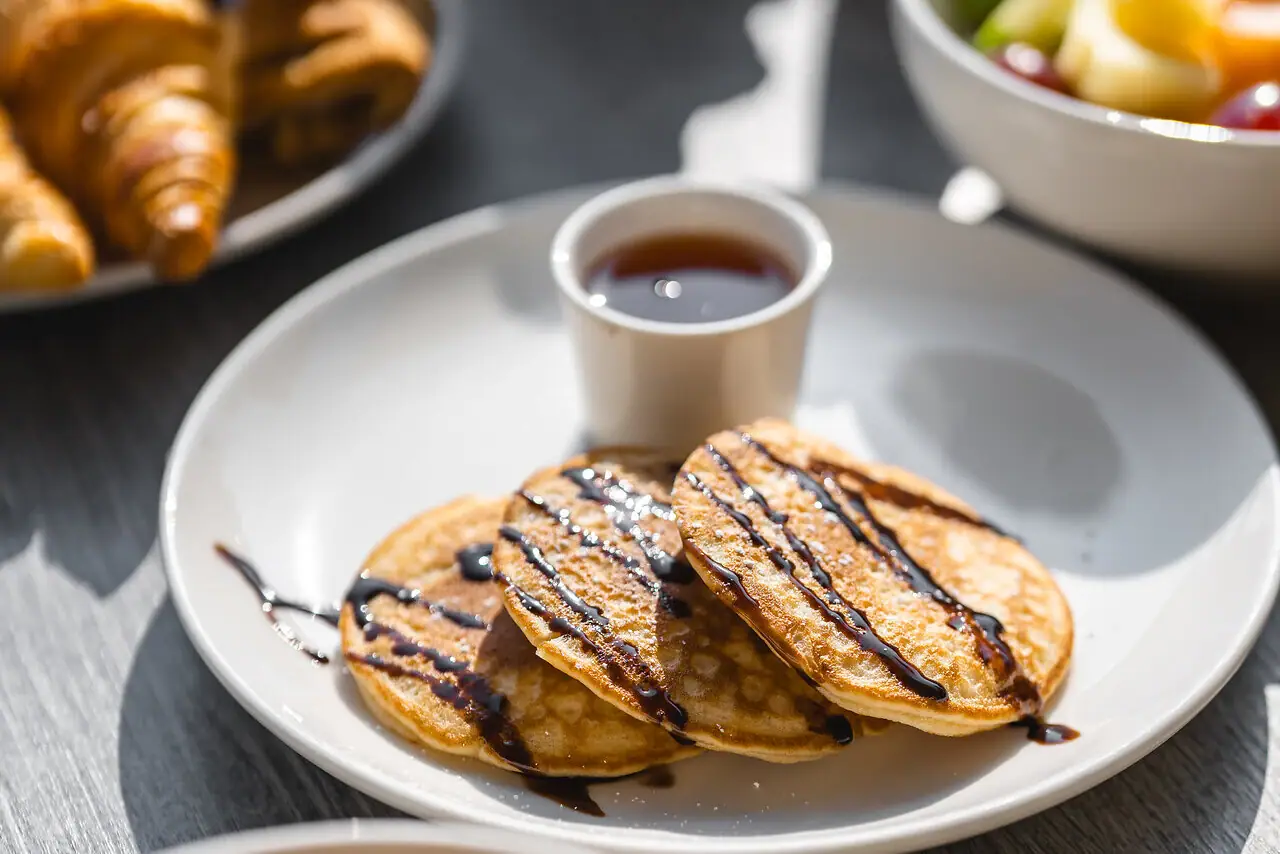 Een bord met pannenkoeken en stroop en een beker met stroop.