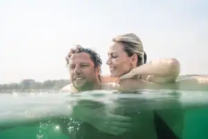 Ein Mann und eine Frau im Wasser, beide lächelnd.