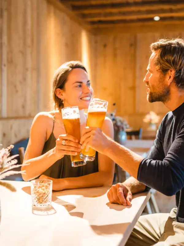 Een man en een vrouw zitten aan een tafel met glazen bier.
