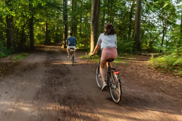 Een man en een vrouw fietsen op een bospad.