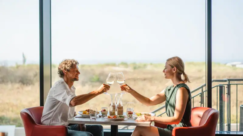 Restaurant bij aja Warnemünde Een man en een vrouw zitten aan een tafel met glazen wijn.