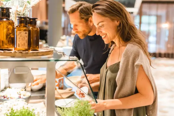 Een man en een vrouw staan voor een buffet.