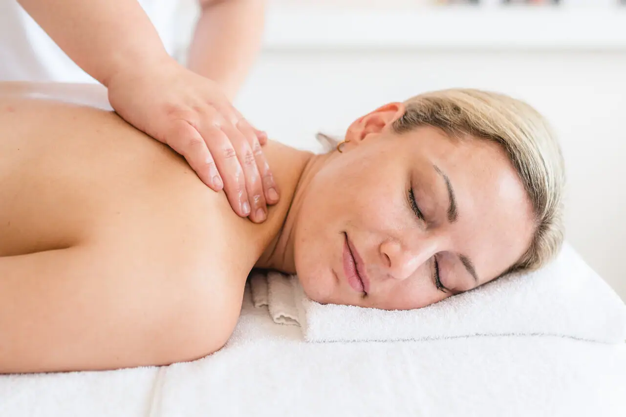 Massage Een vrouw ligt op een witte handdoek met haar ogen dicht.