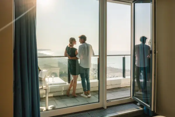 Balkon Ausblick Ein Mann und eine Frau stehen auf einem Balkon mit Blick auf einen Strand.