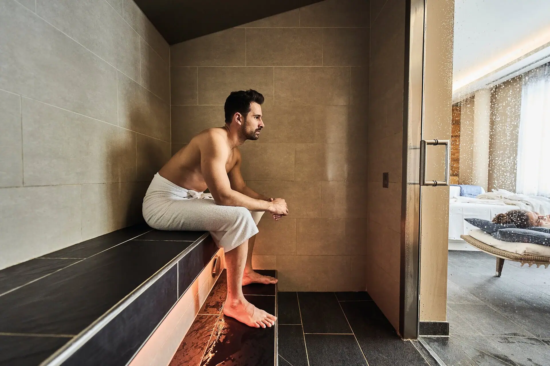 Een man zit op een bank in het stoombad