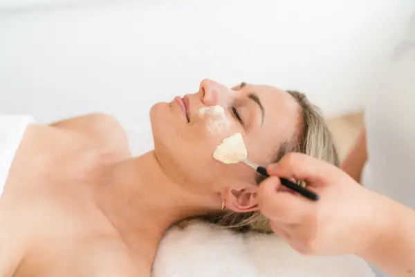 Gezichtsbehandelingen Een vrouw ligt met een borstel op haar gezicht.