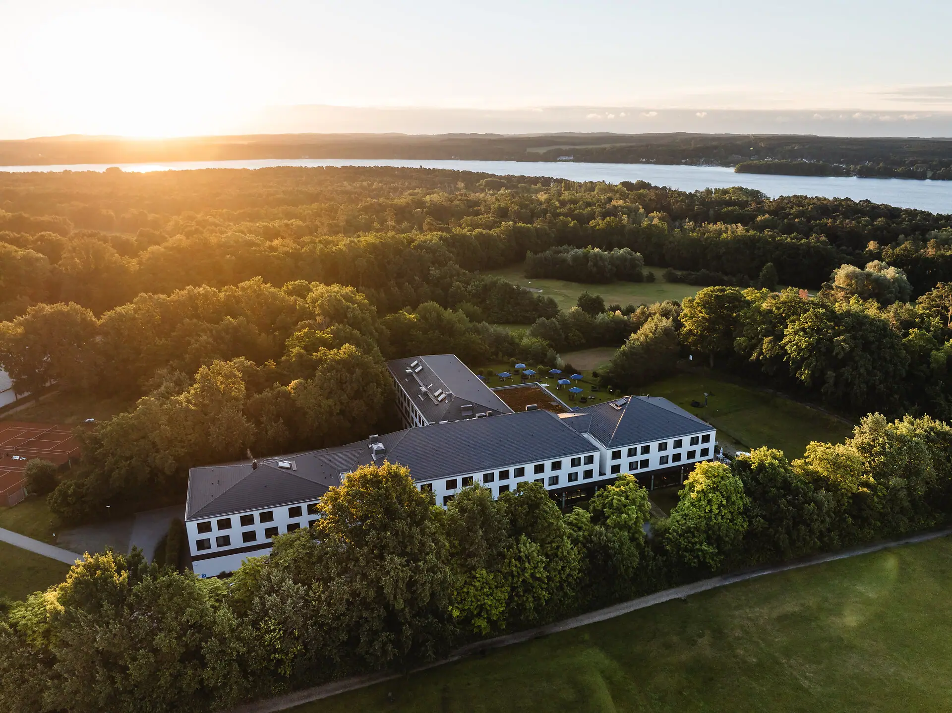 Ein Gebäude umgeben von Bäumen und einem Gewässer.