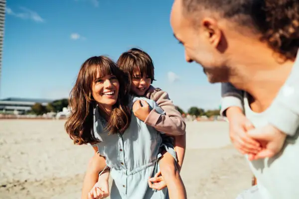 Een man en een vrouw houden een kind vast op het strand.