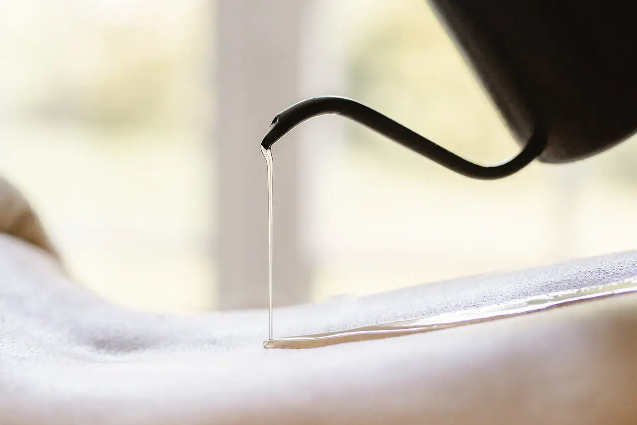 Lentefrisheid massage Een persoon giet olie op de rug van een andere persoon.