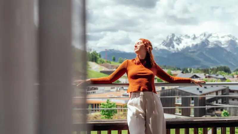 Kamer met balkon Een vrouw staat op een balkon met haar armen wijd uitgestrekt.