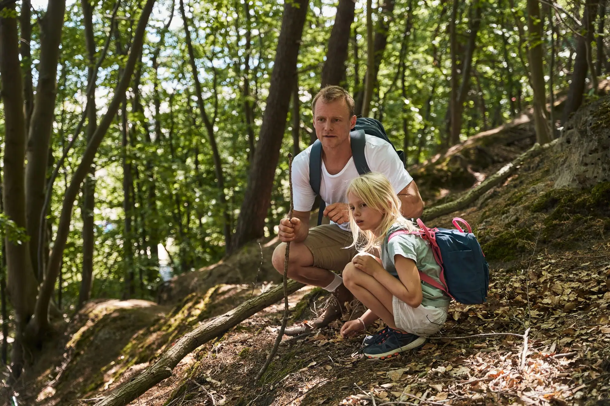 Een man en een meisje zitten op een heuvel in het bos.