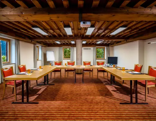 Conferentieruimte Conferentieruimte met U-vormige tafels, stoelen en ramen.