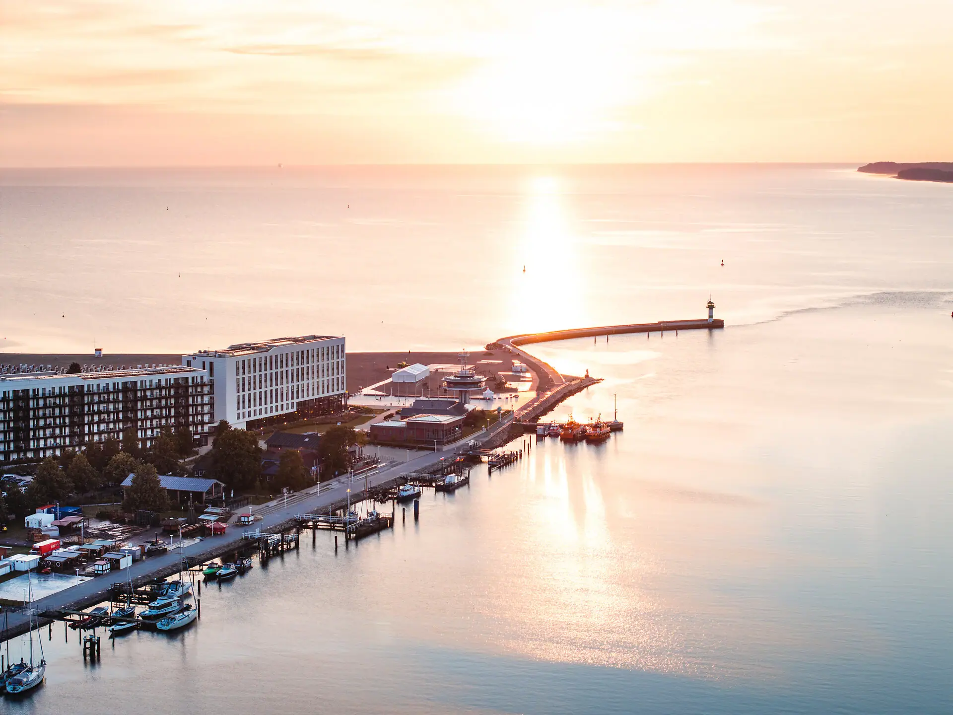 De aja Travemünde ligt direct aan het water met een vuurtoren op de achtergrond.