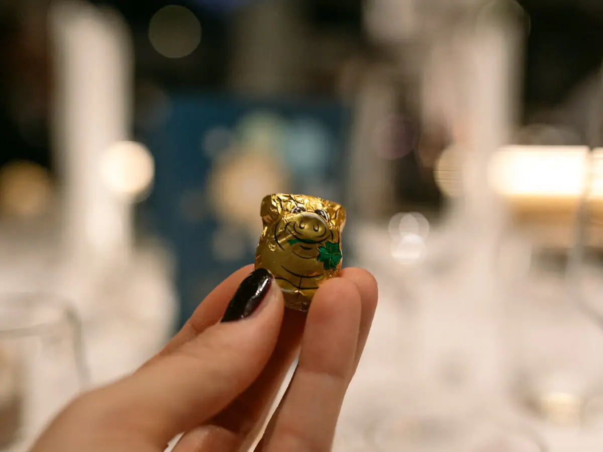 Eén hand houdt een klein verpakt chocoladevarken vast.