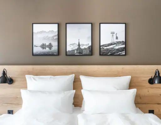 Bed met kussen Een bed met witte kussens en een houten hoofdeinde, met een afbeelding van een berg en een skilift erboven.