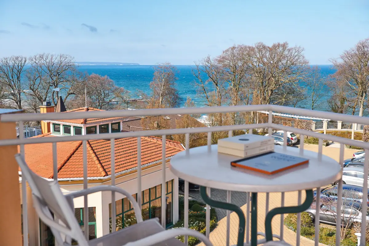 Tweepersoonskamer met balkon Een tafel met een boek erop en uitzicht op zee.