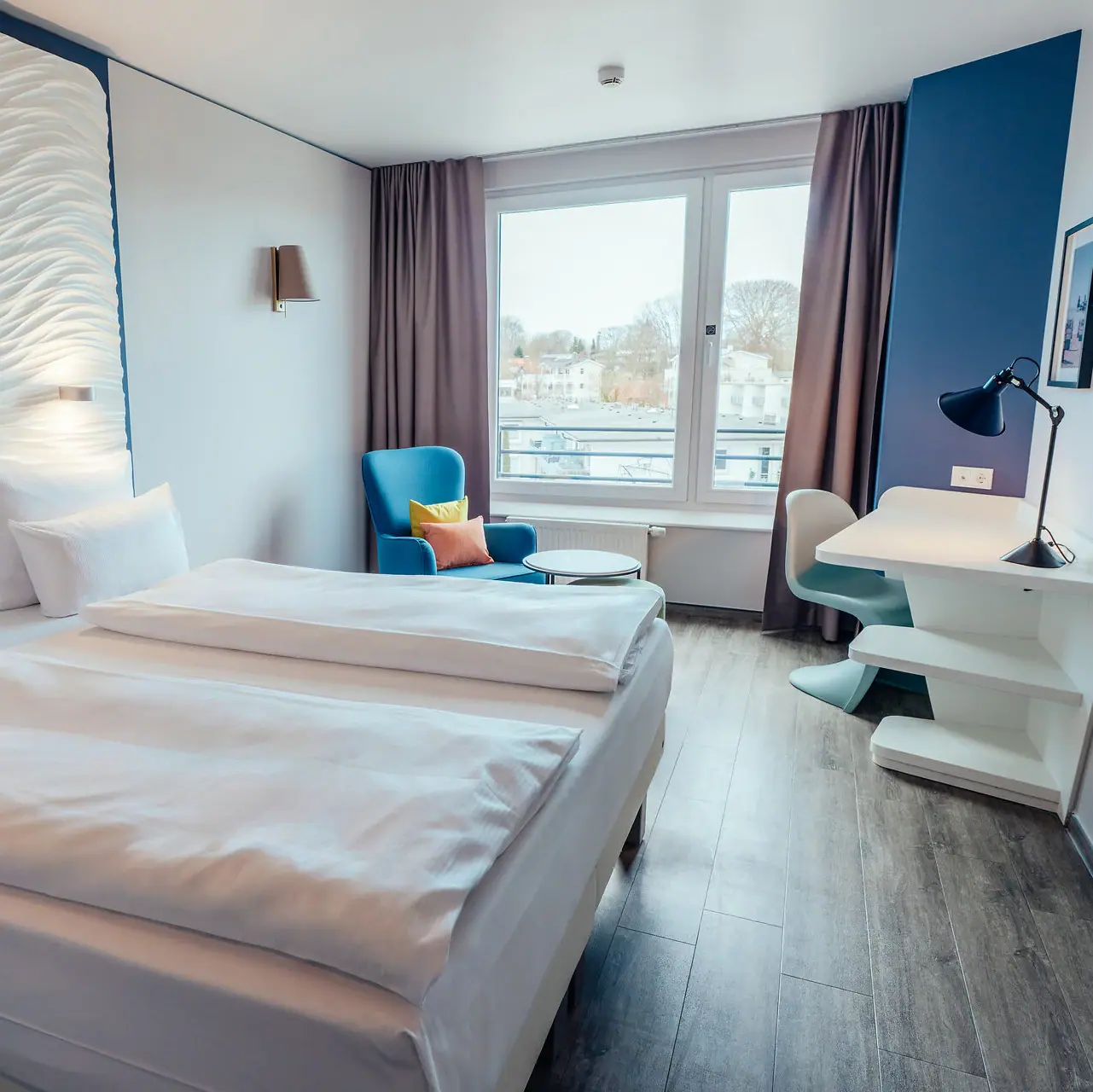 Tweepersoonskamer Een kamer met twee bedden en een tafel.