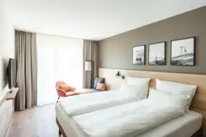 Tweepersoonskamer Een kamer met twee bedden en een stoel.