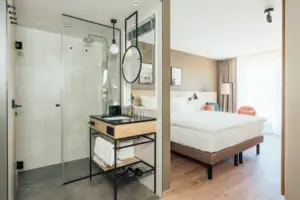 Tweepersoonskamer Een badkamer met glazen douche en een bed.