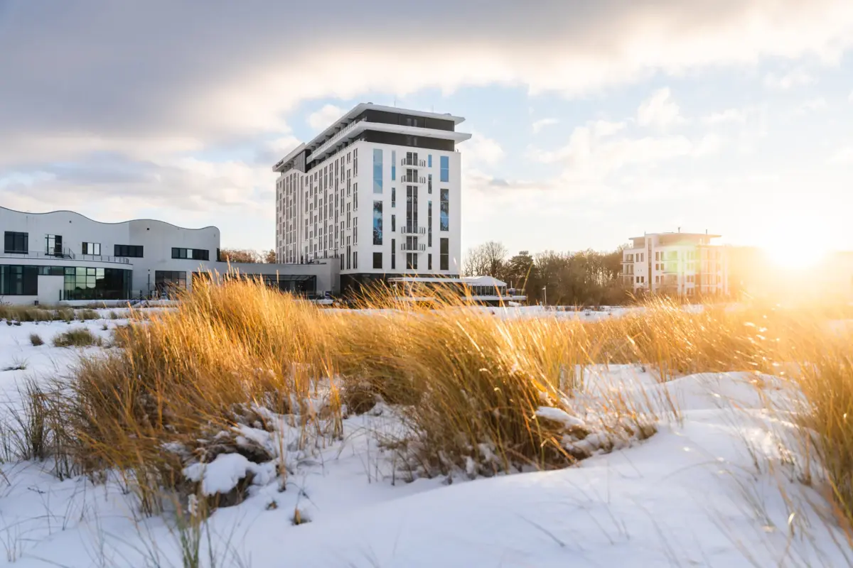aja Warnemünde Hoog gras voor een gebouw in de open lucht, met een bewolkte hemel.