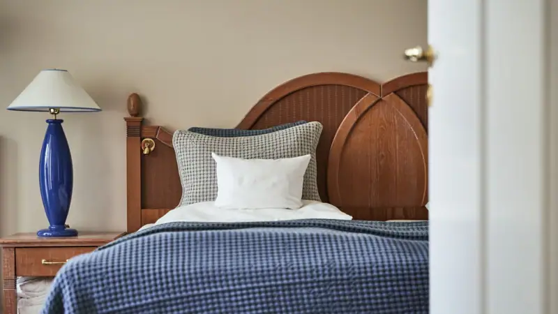 Bed met blauwe deken en wit kussen