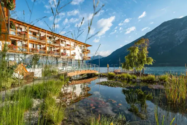 Ein Gebäude neben einem Gewässer mit Bäumen und Wolken im Hintergrund.