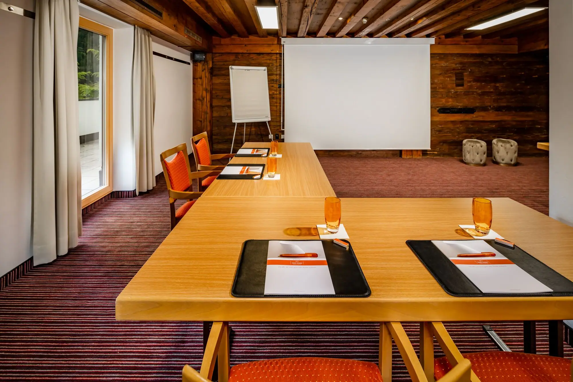 Vergaderzaal Een kamer met een groot wit scherm en verschillende tafels.