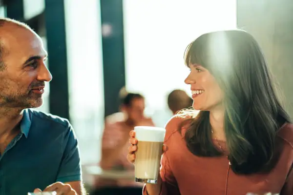 Een man en een vrouw houden een glas koffie vast.