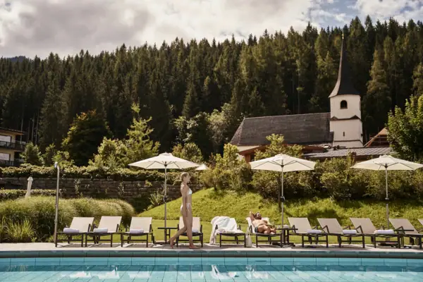 Zwemwereld bij aja Bergresort Werfenweng Een vrouw loopt langs een zwembad.