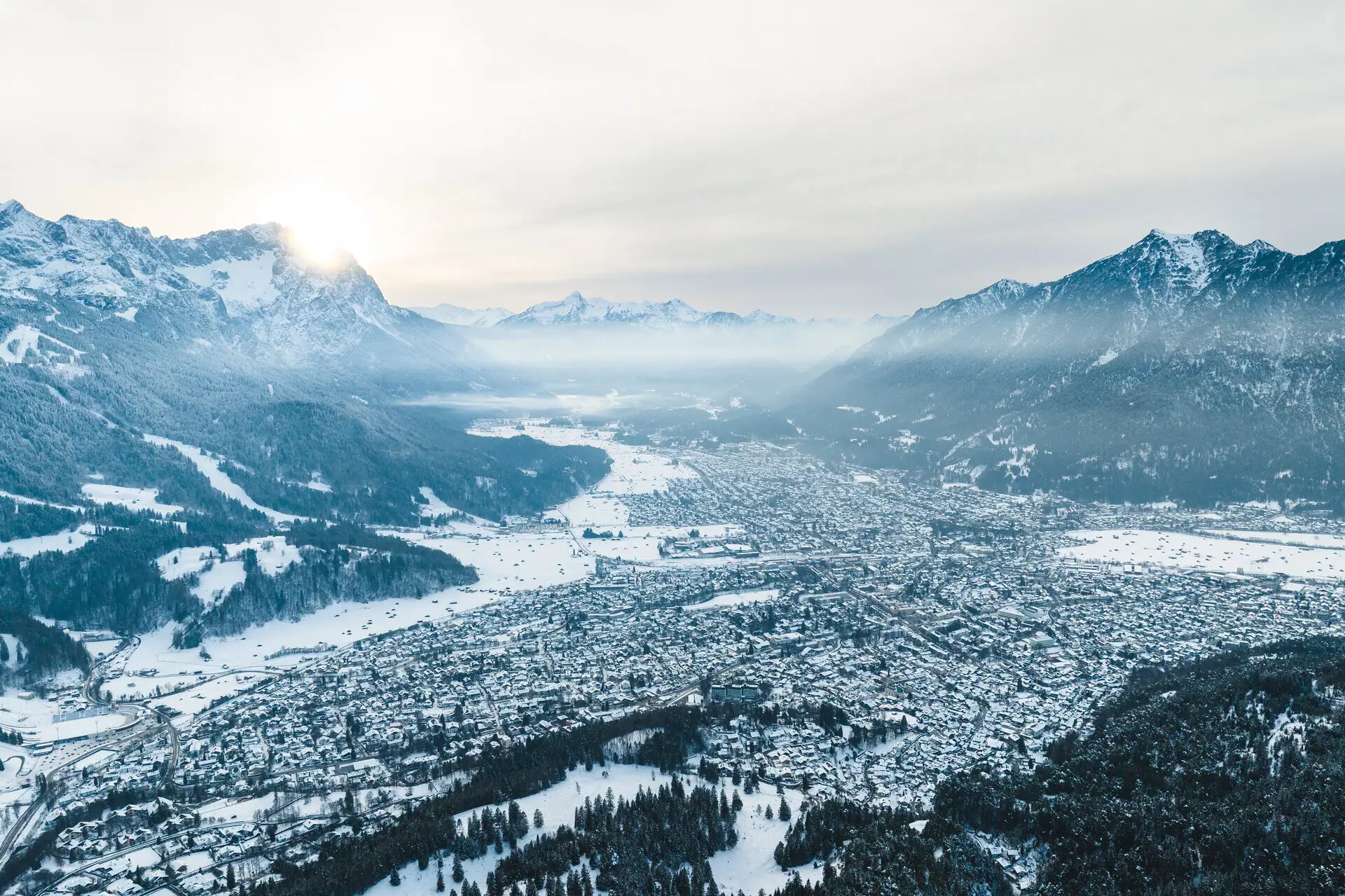 Aankomst per vliegtuig Besneeuwde stad met berglandschap op de achtergrond.