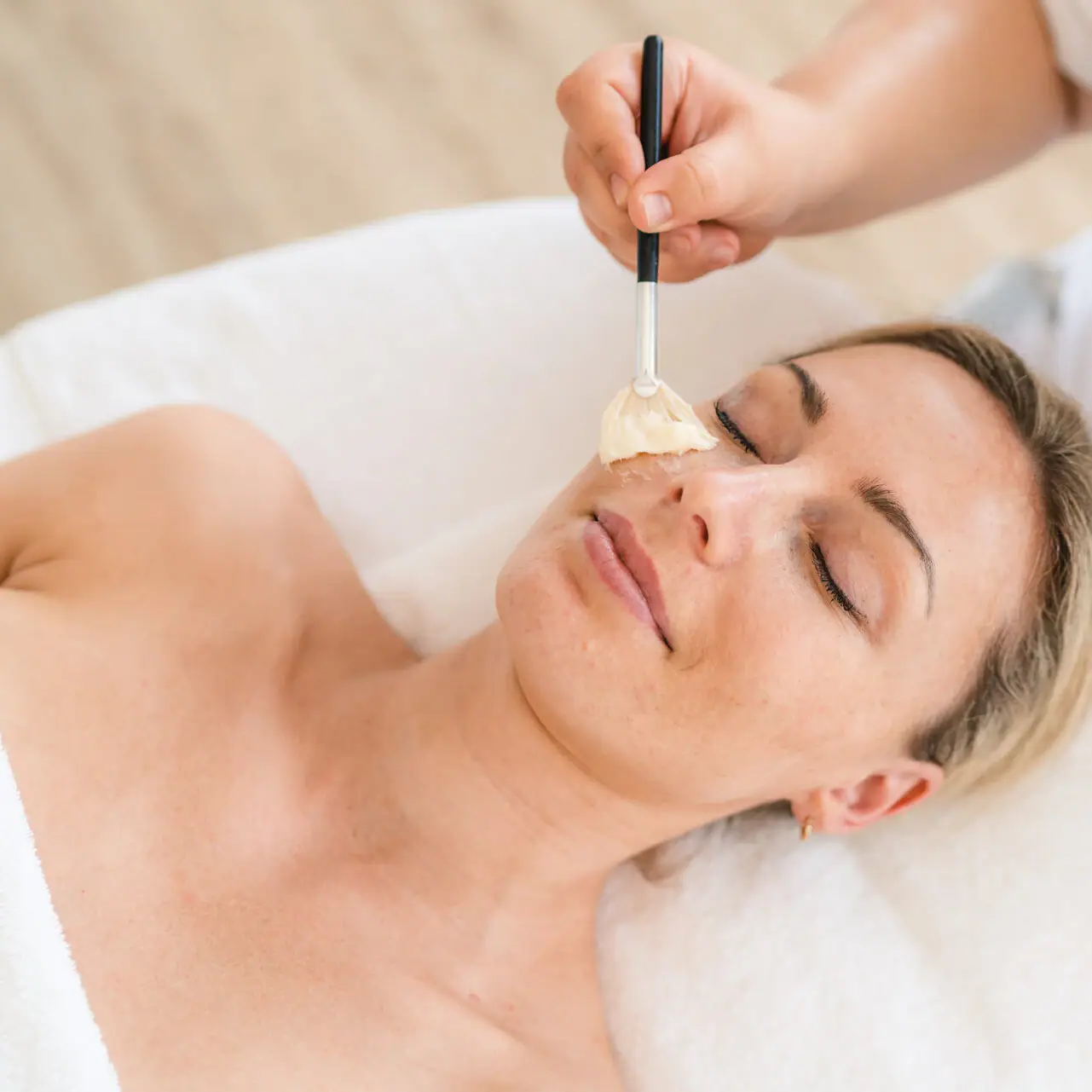 Een vrouw ligt met een verfkwast op haar gezicht.