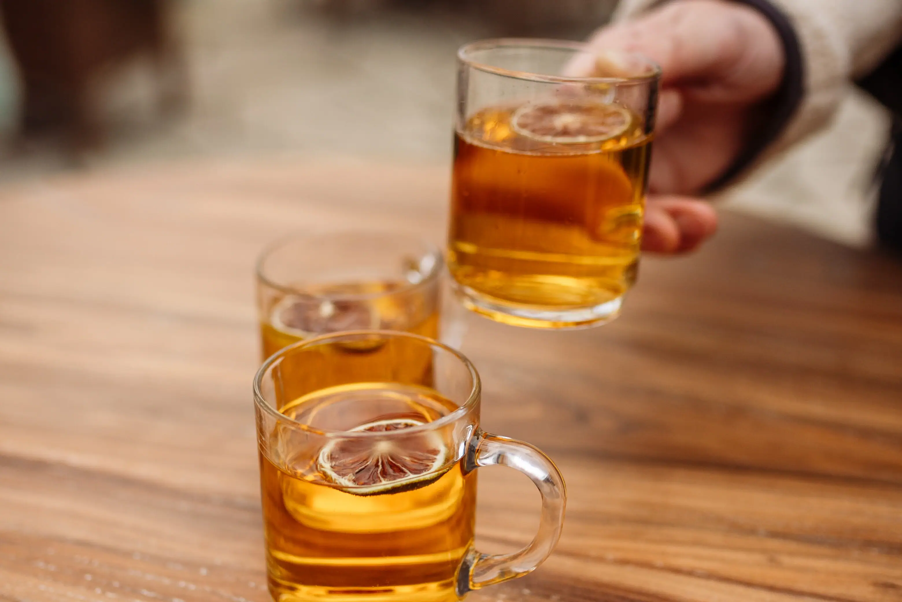 Eén hand houdt een glas met een alcoholische drank vast.