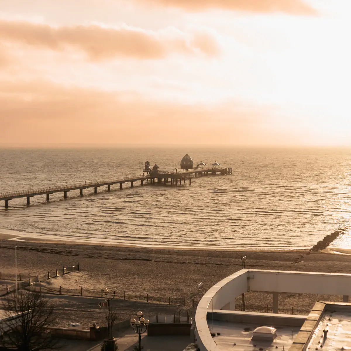 Een lange pier in het water onder een bewolkte hemel.
