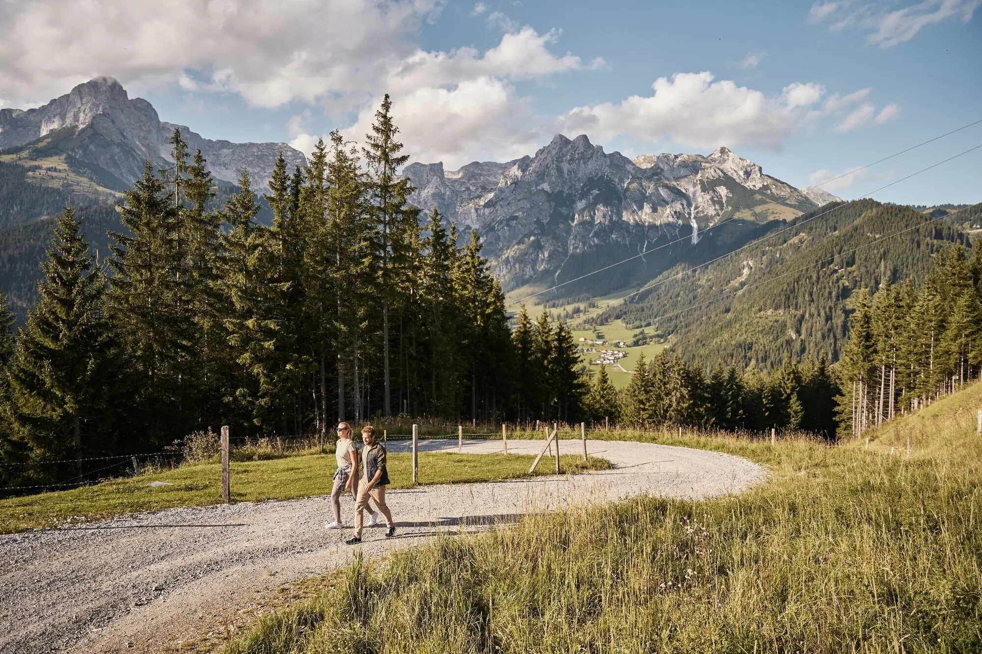 Wandelpad Twee mensen lopen op een grindpad voor een bergketen.