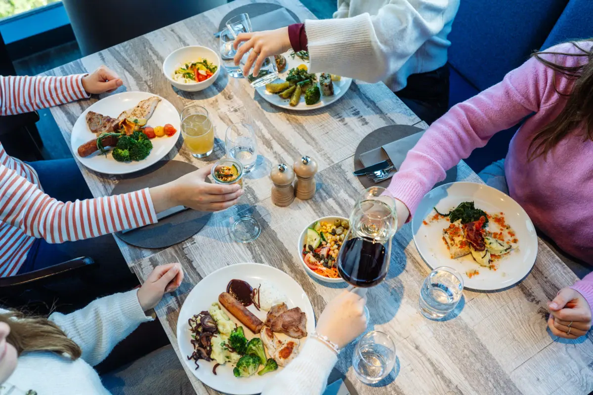 Diner Een groep mensen zit aan een tafel met borden eten.