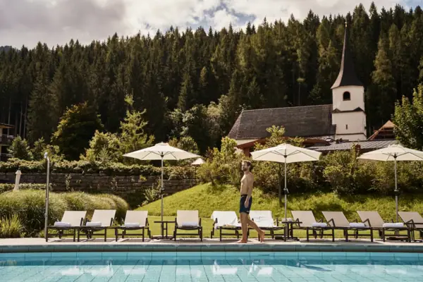 Een man loopt langs een zwembad.