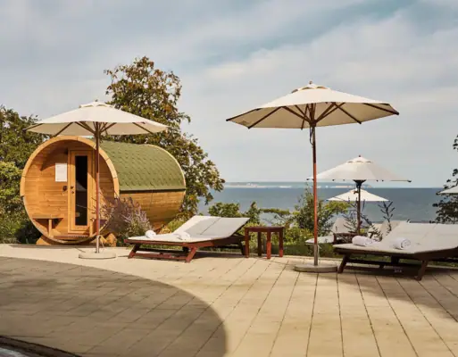 Ligstoelen en parasols naast een ton en een waterpartij.