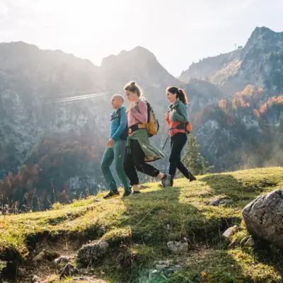 Een groep mensen loopt op een heuvel met bergen op de achtergrond.