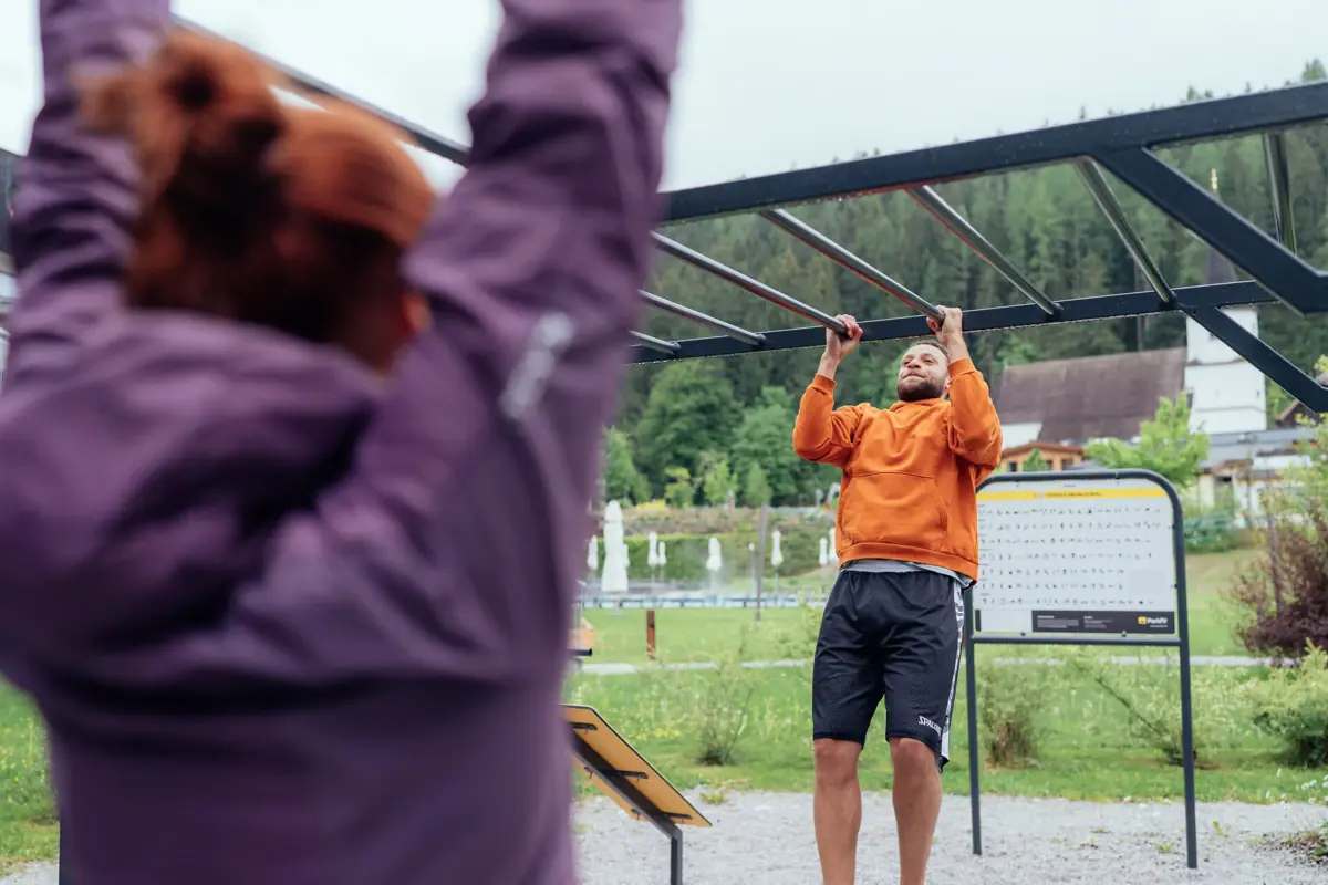 Fitness in de buitenlucht Een man houdt zich vast aan een paar klimstangen.
