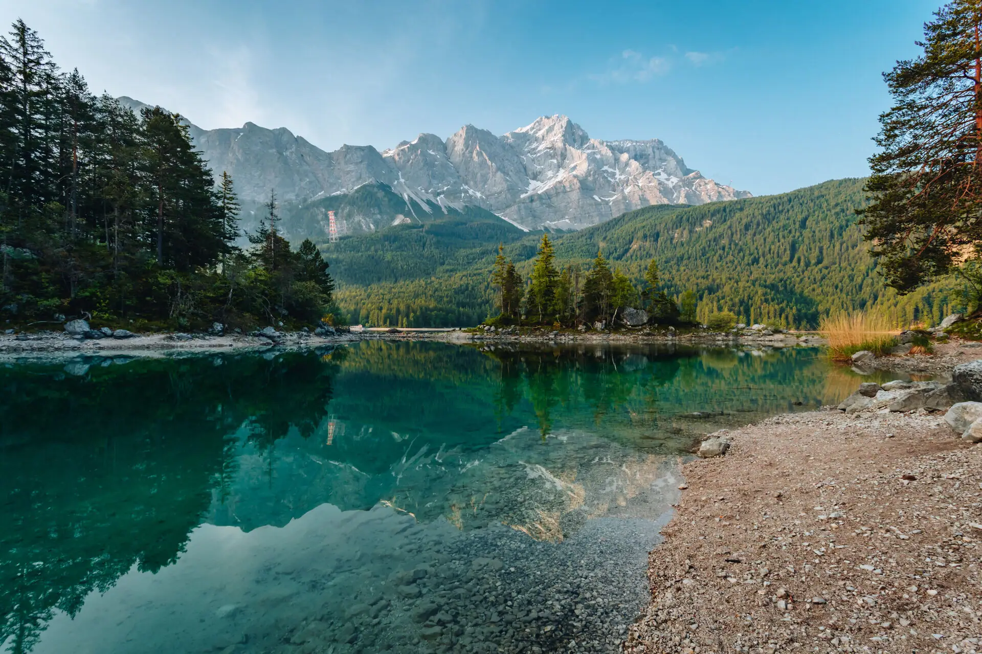 Eibsee Een watermassa met bomen en bergen op de achtergrond.