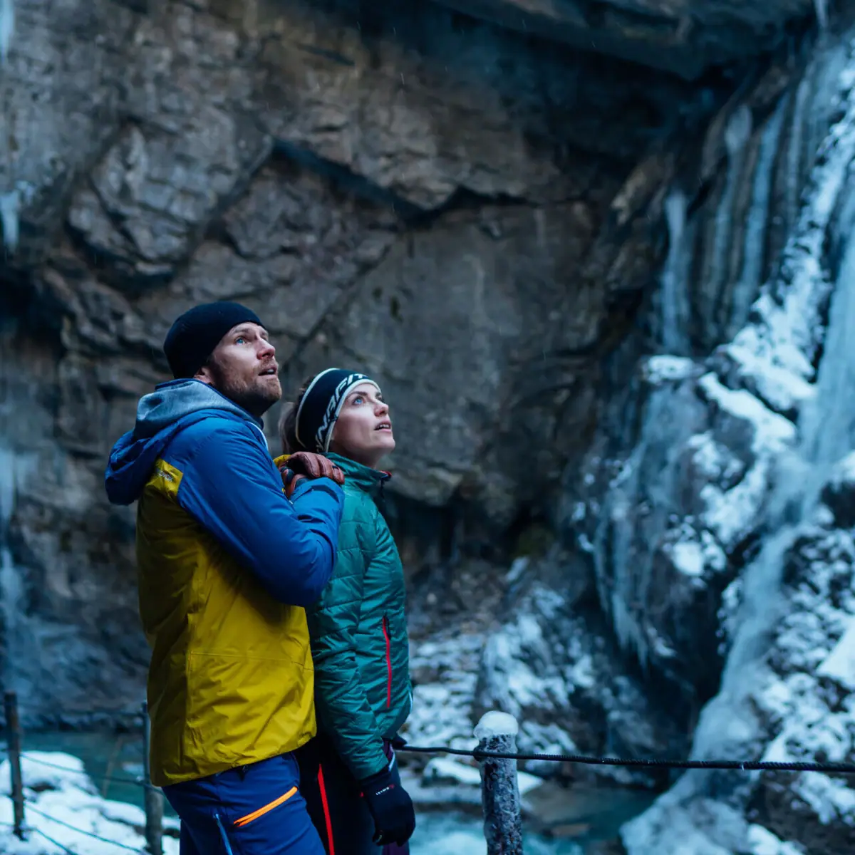 Een man en een vrouw staan in de Partnachklamm, te midden van een winterse natuur.