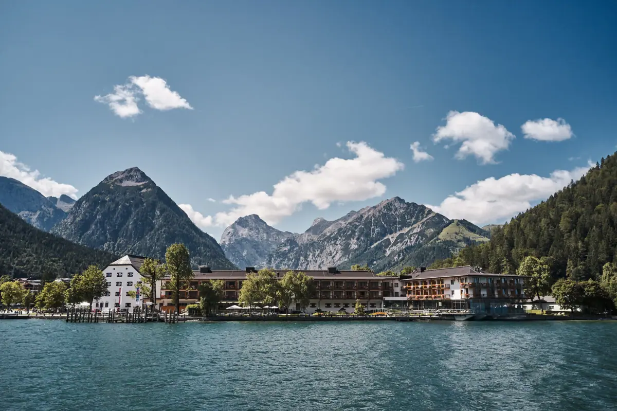 het huis van de vorsten aan de Achensee Een gebouw naast een waterpartij onder een bewolkte hemel.