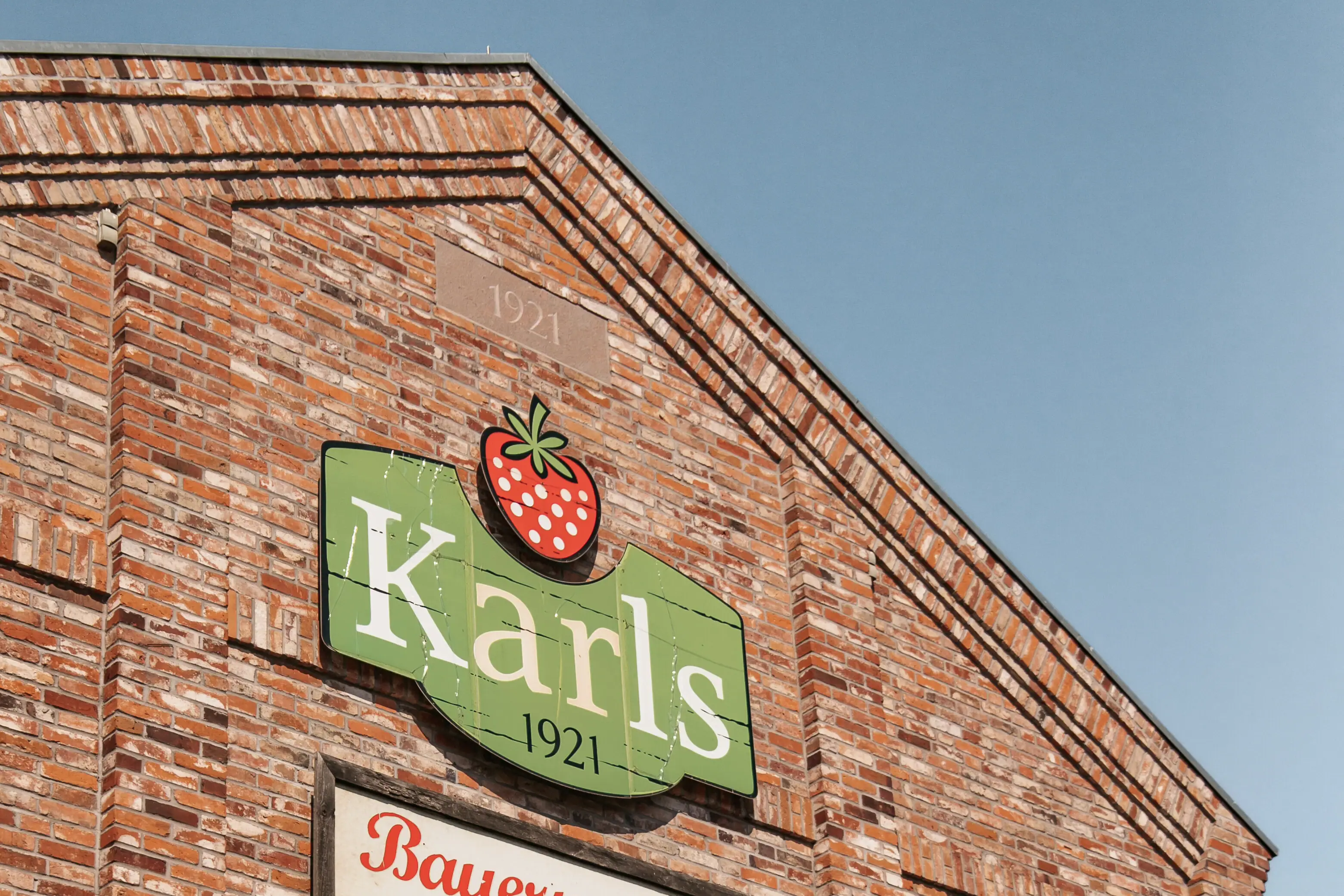Karl's aardbeienboerderij Een bord op de zijkant van een bakstenen gebouw.