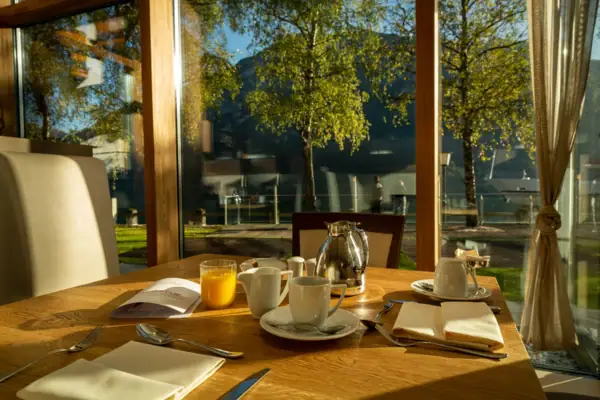 Ein Tisch mit einer Teekanne und Tassen vor einer Glaswand.