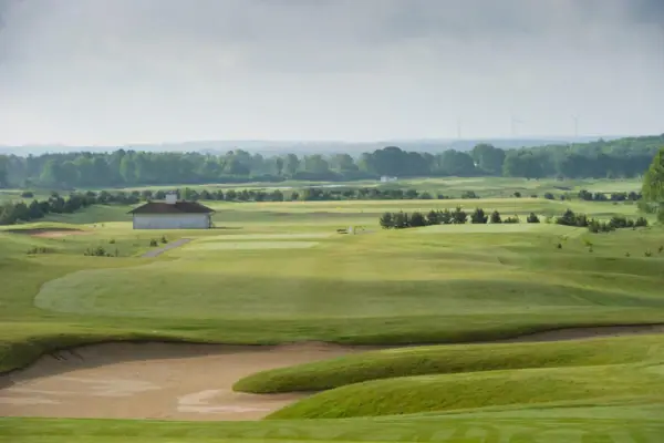 Golfbaan met een gebouw en bomen op de achtergrond.