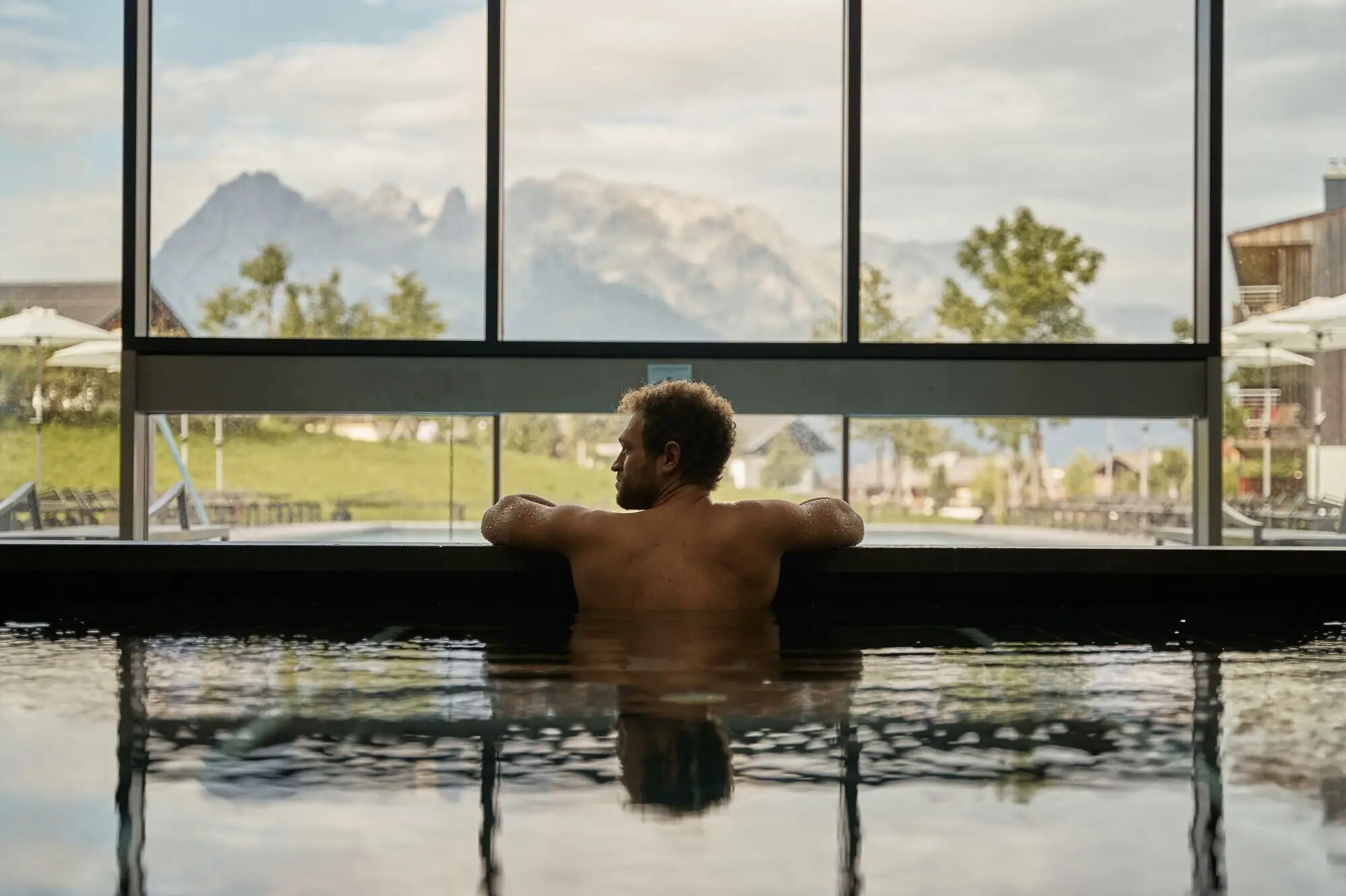 Overdekt zwembad aja Werfenweng Man zwemt in een zwembad met uitzicht op bergen en bomen.