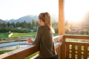 Suite met balkon aja Ruhpolding Een vrouw staat op een veranda en kijkt neer op een vallei.